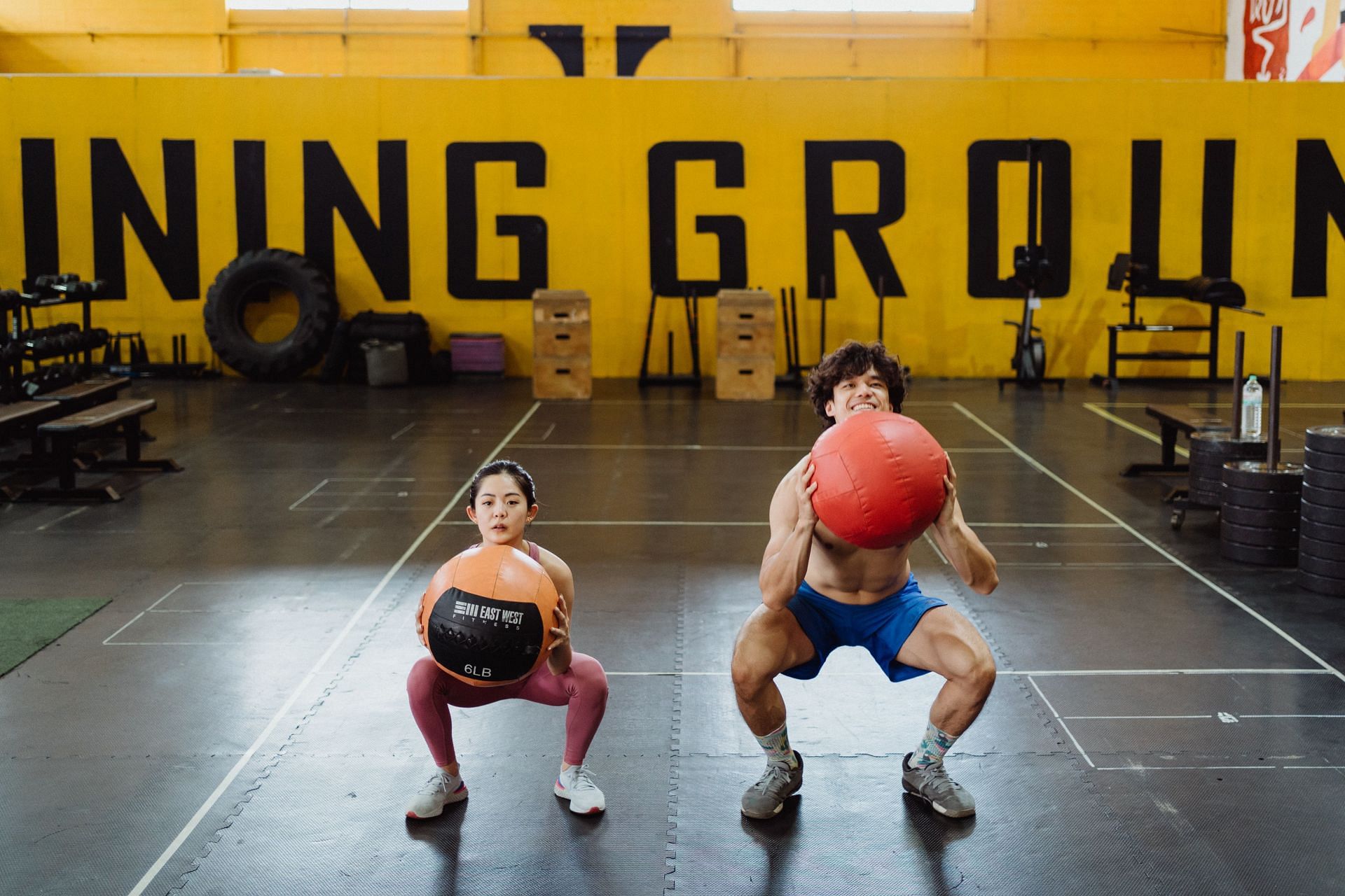 Couple performing medicine ball squats. (Image via Unsplash/ Ketut Subiyanto)